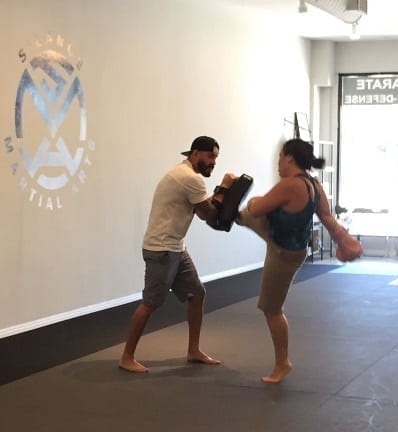 Tina Austin with a roundhouse high kick against the pad in the Muay Thai Kickboxing class