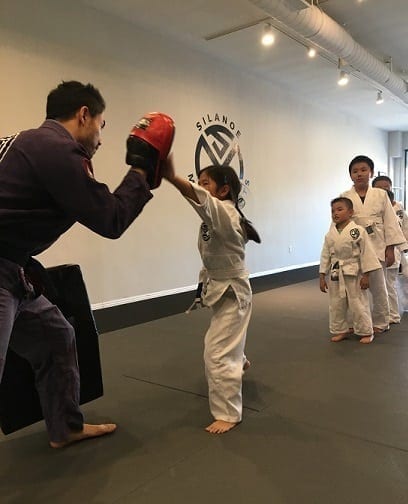 Sammi in the BJJ kids program working with Professor Gino on the punch mitt