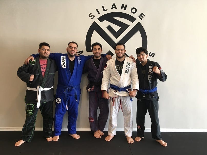 Professor Gino with student of the month Jacob and his family posing in front of the wall after belt promotions