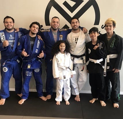 BJJ Kids student Juliet from Covina with her family in front of the Silanoe logo